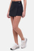 Woman wearing a black skort with waist clasp and white sneakers on a white background. 