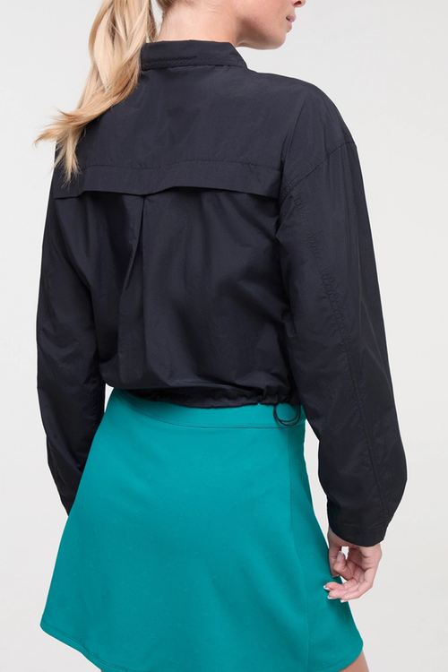 Back view of woman wearing a black jacket and teal skirt on a white background. #color_black