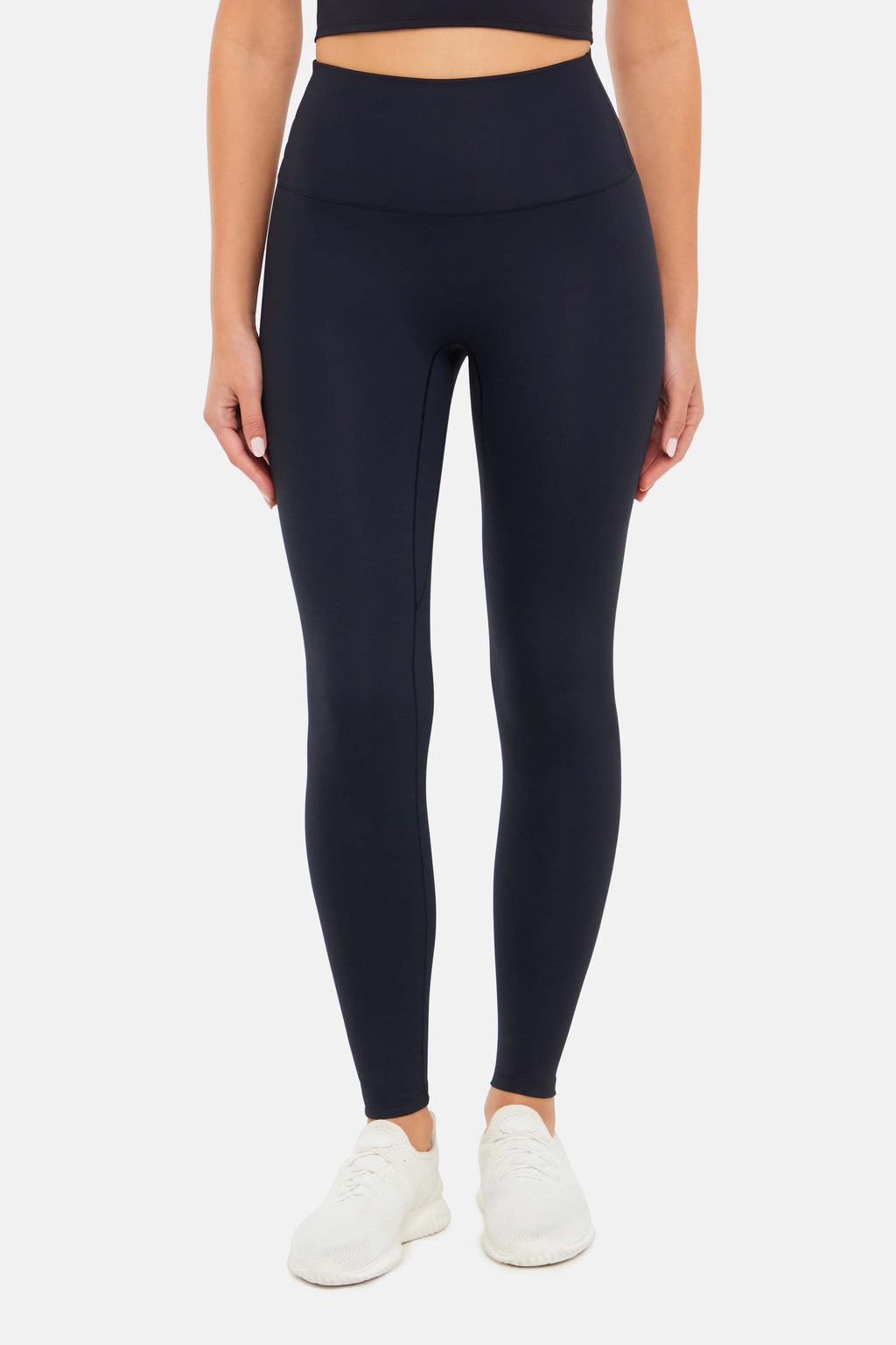 Front view of woman wearing black leggings on a white background. #color_black