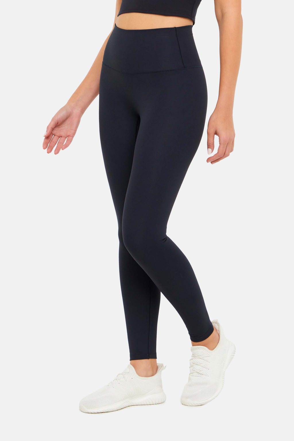 Side view of woman wearing black leggings on a white background. #color_black