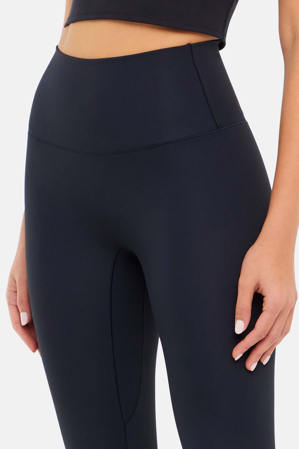 Close up front view of woman wearing black leggings on a white background. #color_black