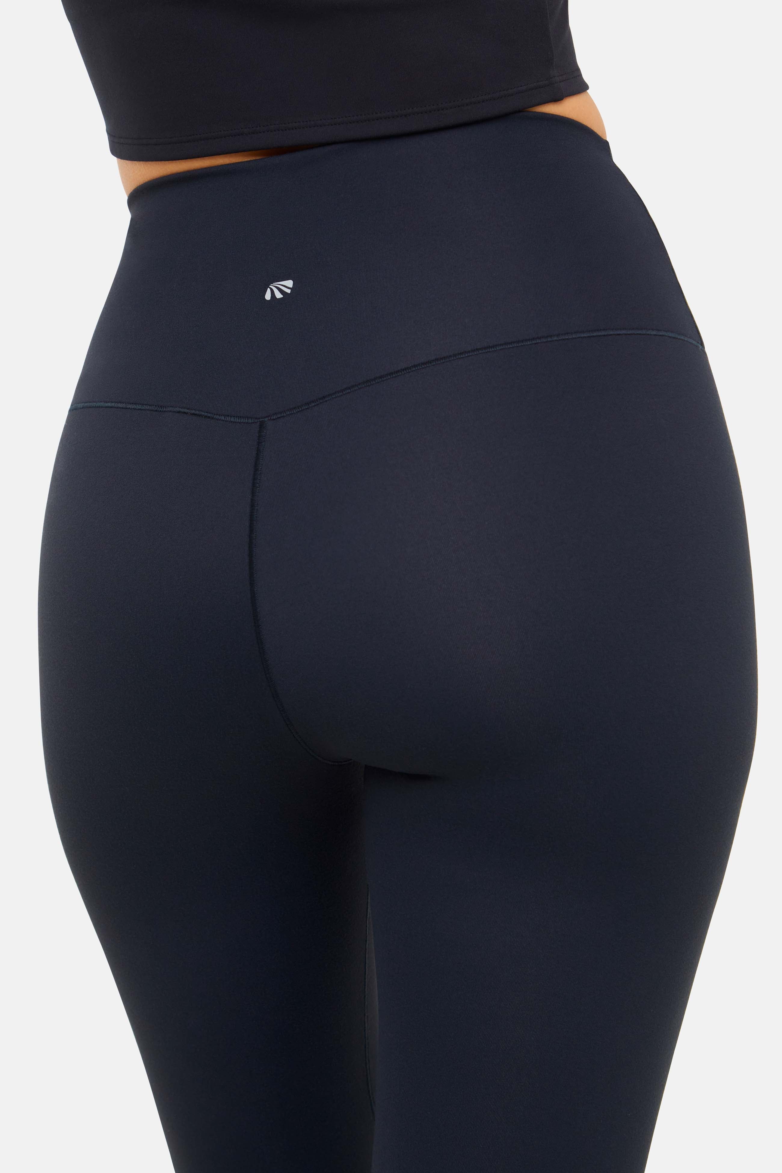 Close up back view of woman wearing black leggings on a white background. 