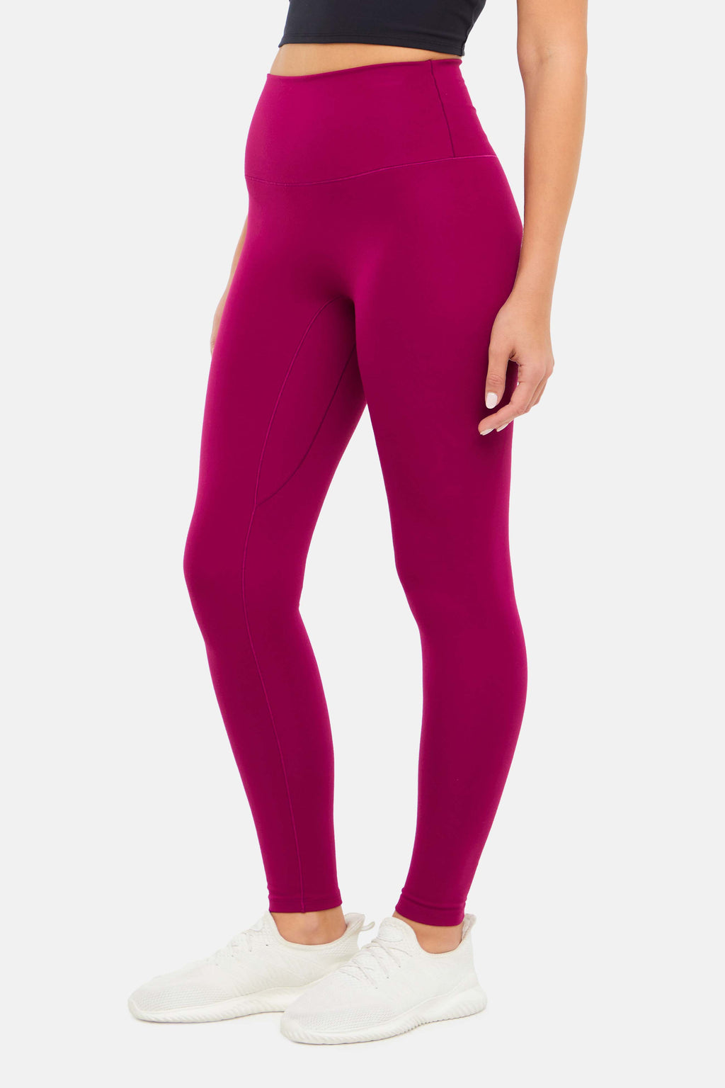 Side view of woman wearing bright burgundy leggings on a white background. #color_magenta-purple