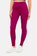 Front view of woman wearing bright burgundy leggings on a white background. #color_magenta-purple