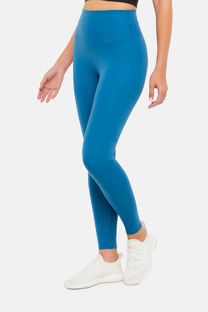 Side view of woman wearing bright blue leggings on a white background. 