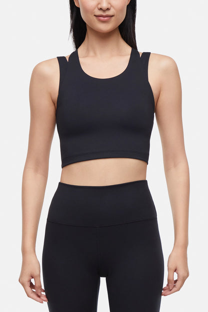 Front view of woman wearing a black sports bra and black leggings on a white background. 