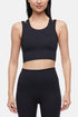 Front view of woman wearing a black sports bra and black leggings on a white background. 