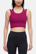 Front view of woman wearing a bright burgundy sports bra and black leggings on a white background. #color_magenta-purple