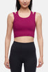 Front view of woman wearing a bright burgundy sports bra and black leggings on a white background. 