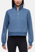 Front view of woman wearing heather blue half-zip pullover with thumbholes on a white background. 