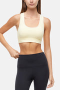Front view of woman wearing a light yellow sports bra with white trim and black leggings on a white background. #color_french-vanilla