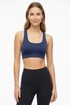 Front view of woman wearing a navy sports bra with white trim and black leggings on a white background. 
