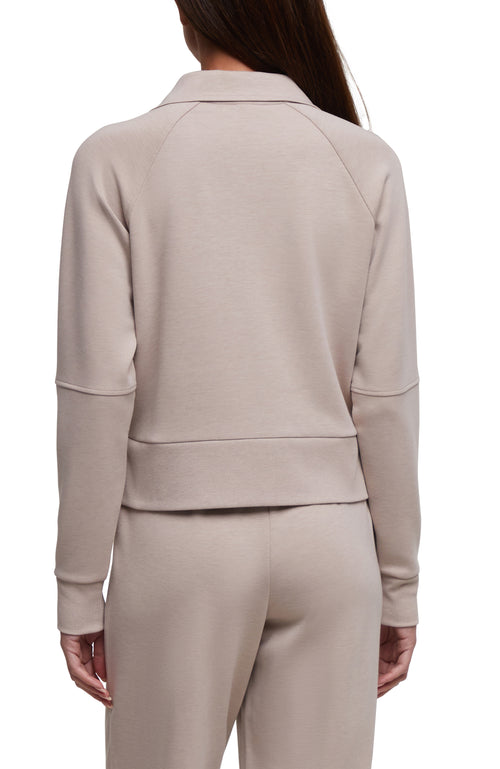 A model shown from the back wearing a light taupe-beige long-sleeve cropped quarter-zip sweatshirt and matching sweatpants against a plain white background. #color_heather-atmosphere