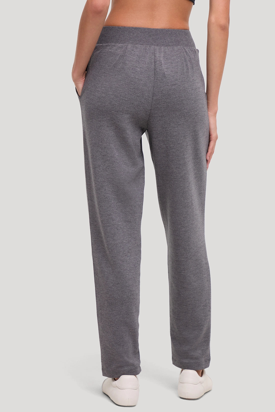 A person shown from the back wearing heather gray lounge pants with an elastic waistband and side pockets, paired with white sneakers, against a light gray studio background. #color_heather-black