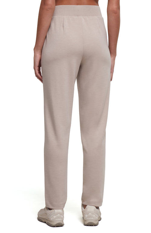 A person shown from the back wearing light beige straight-leg sweatpants and white sneakers against a plain white studio background. #color_heather-atmosphere