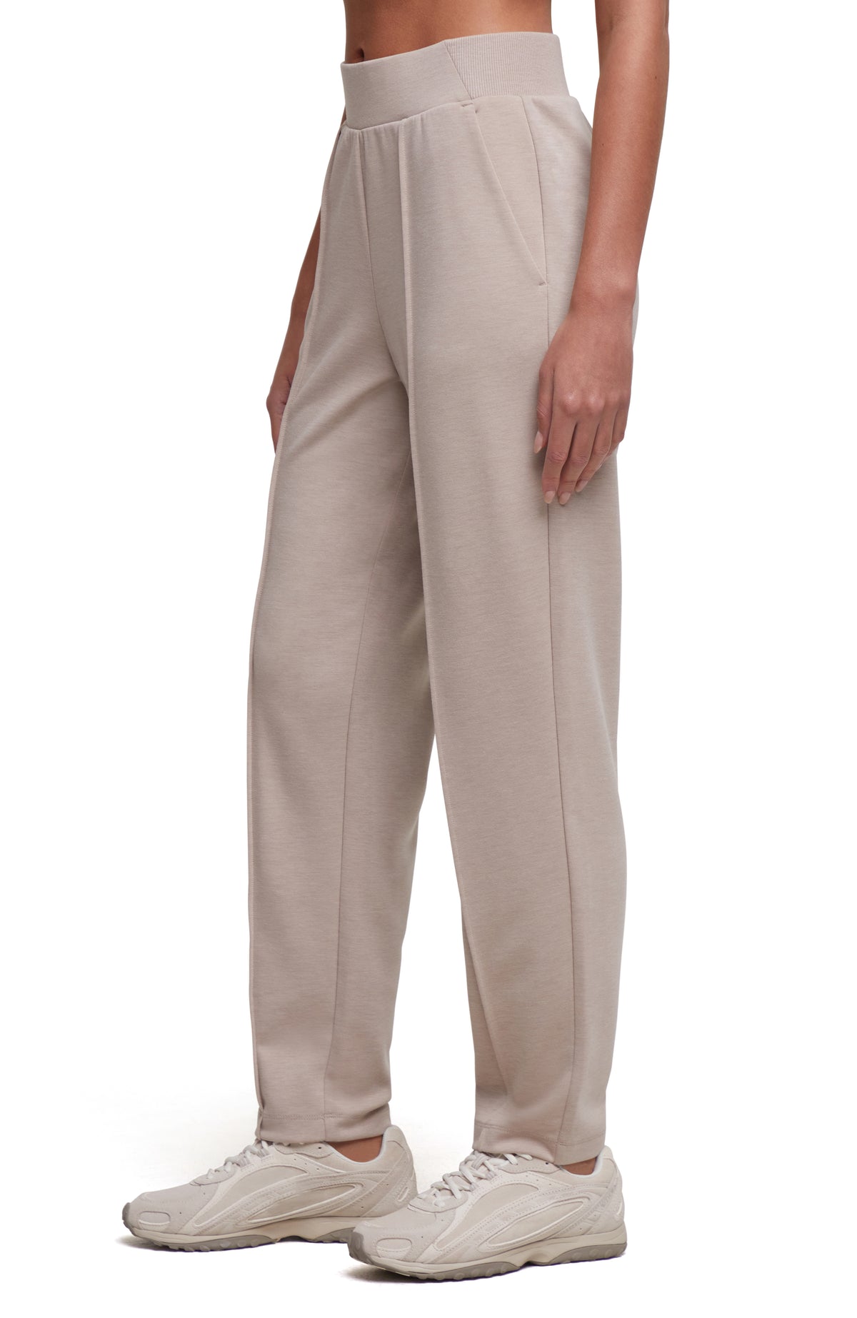 A person wearing light beige wide-leg jogger-style pants and matching sneakers, shown from the waist down against a plain white studio background. #color_heather-atmosphere