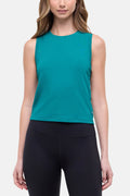 Front view of woman wearing a teal sleeveless top and black leggings on a white background. #color_quetzal-green