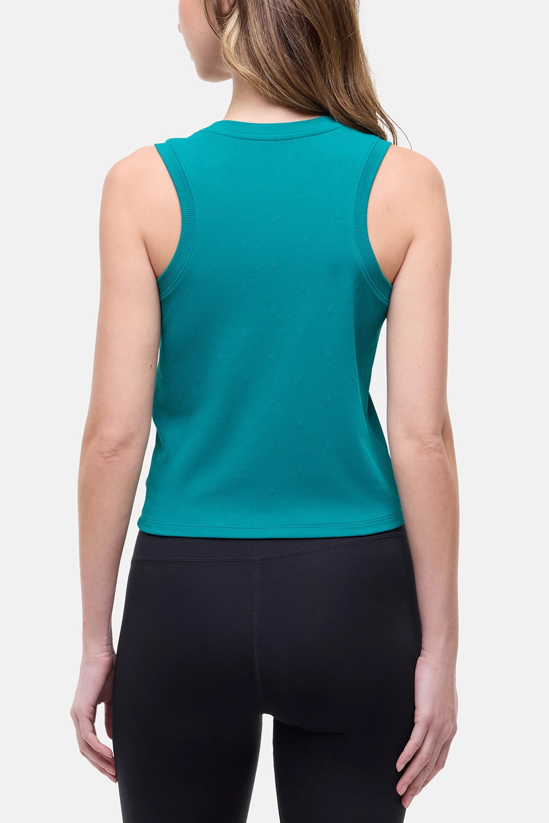 Back view of woman wearing a teal sleeveless top and black leggings on a white background. 