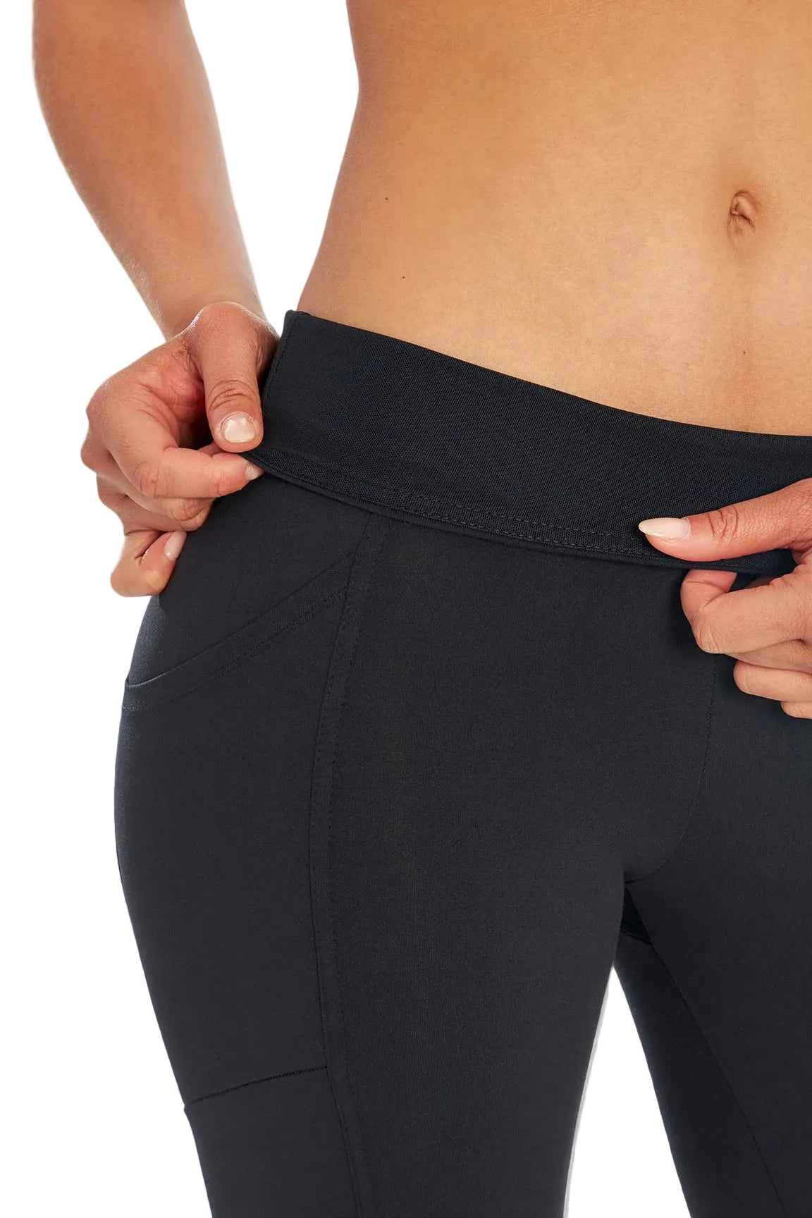 Close up front view of woman wearing black leggings folding over waistband on a white background. 