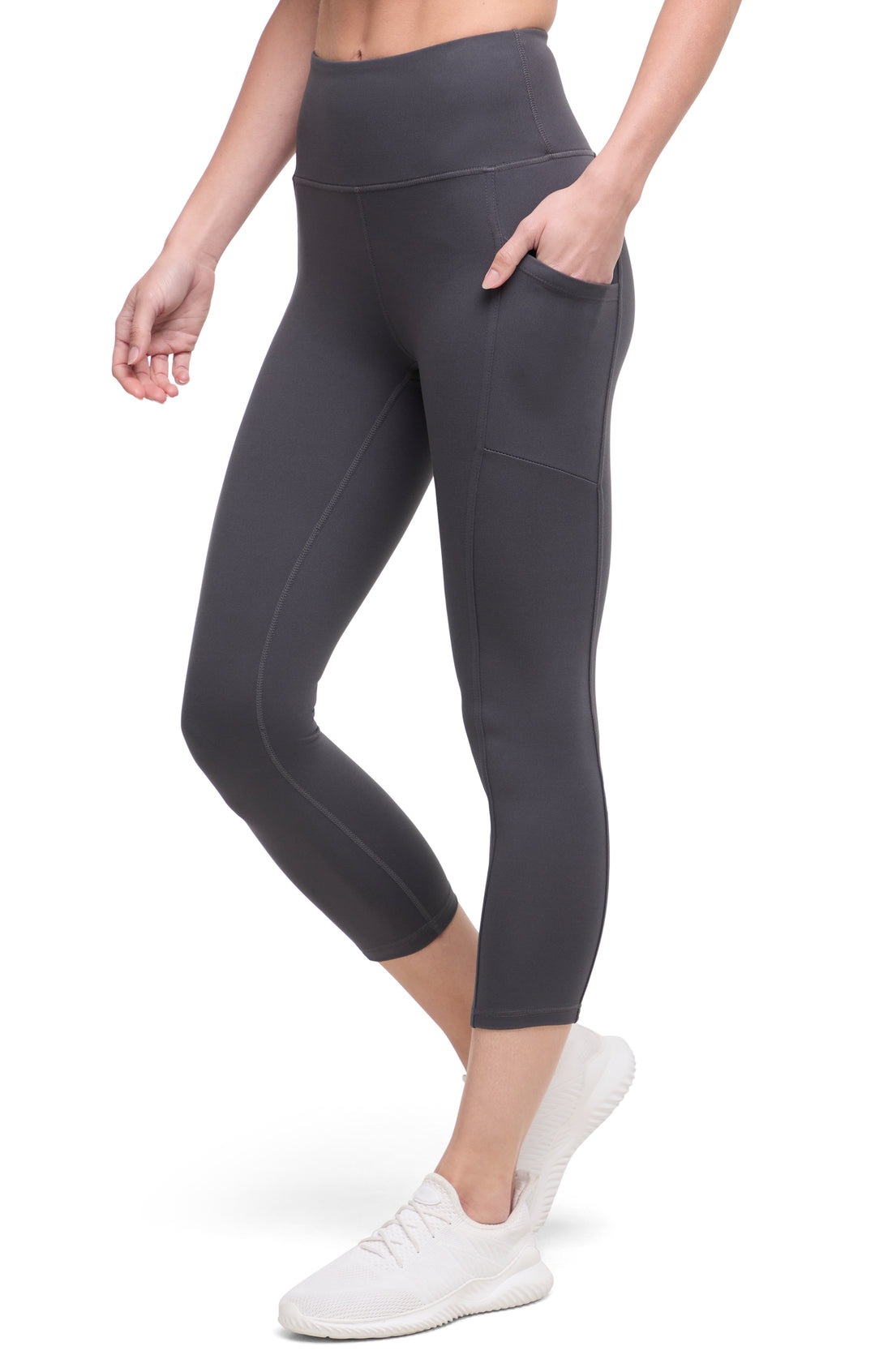 Front of woman wearing dark gray leggings with a white background. 