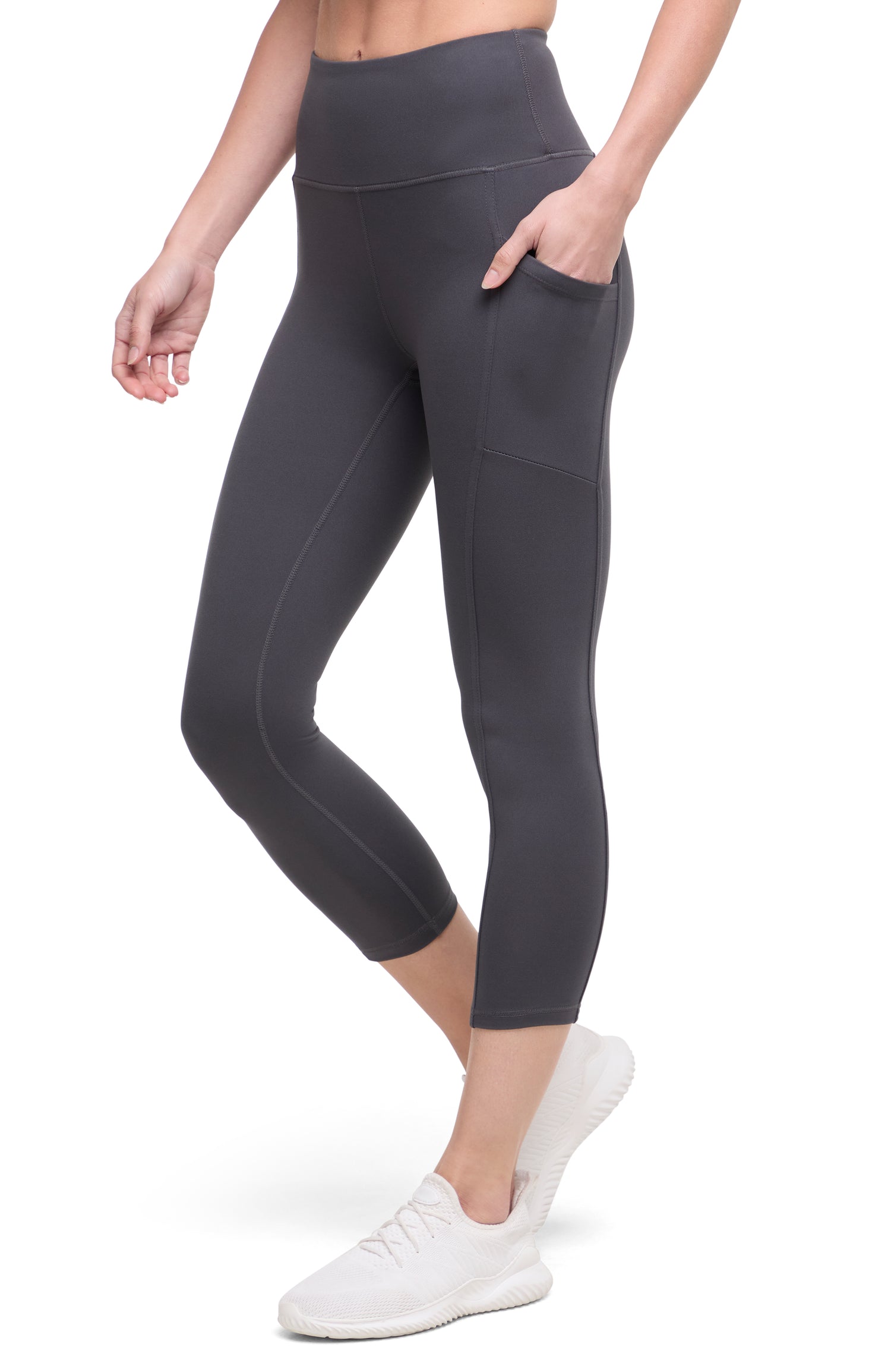 Front of woman wearing dark gray leggings with a white background. 