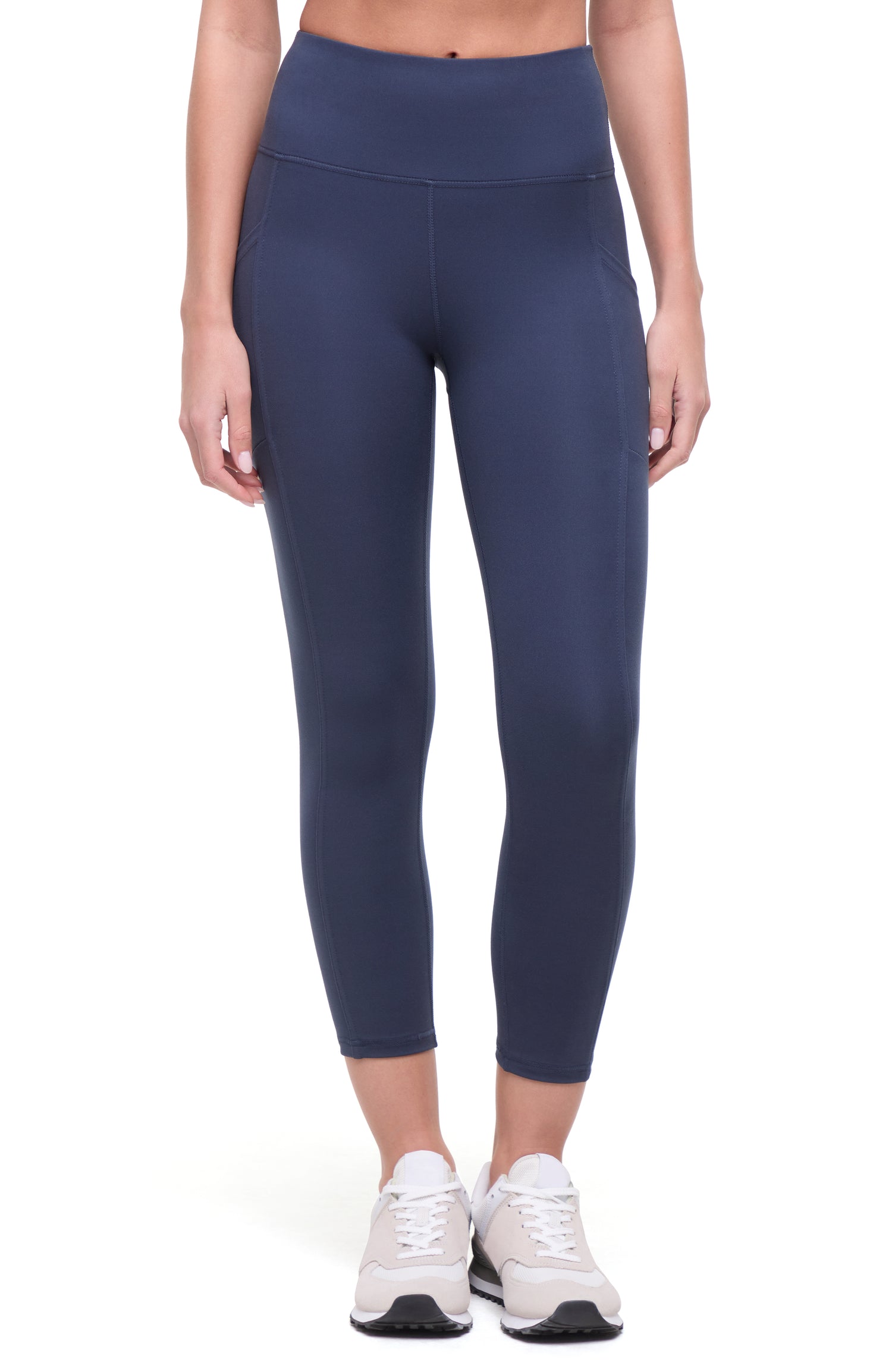 Front view of woman wearing navy blue leggings on a white background. 