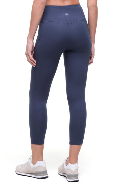Back view of woman wearing navy blue leggings on a white background. 