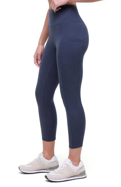 Side view of woman wearing navy blue leggings on a white background. 