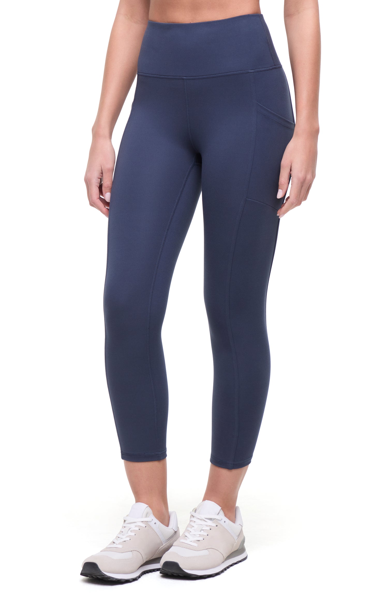 Front view of woman wearing navy blue leggings on a white background. 
