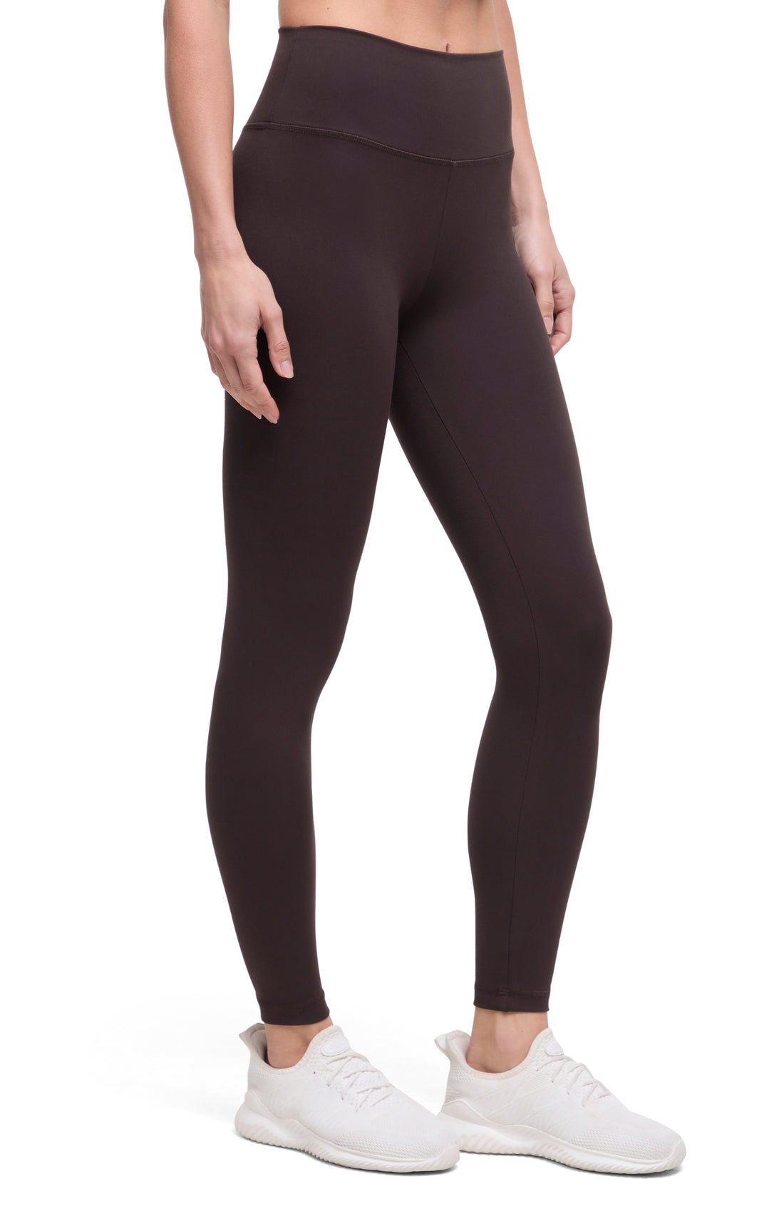 Front view of woman wearing dark brown leggings with a white background.