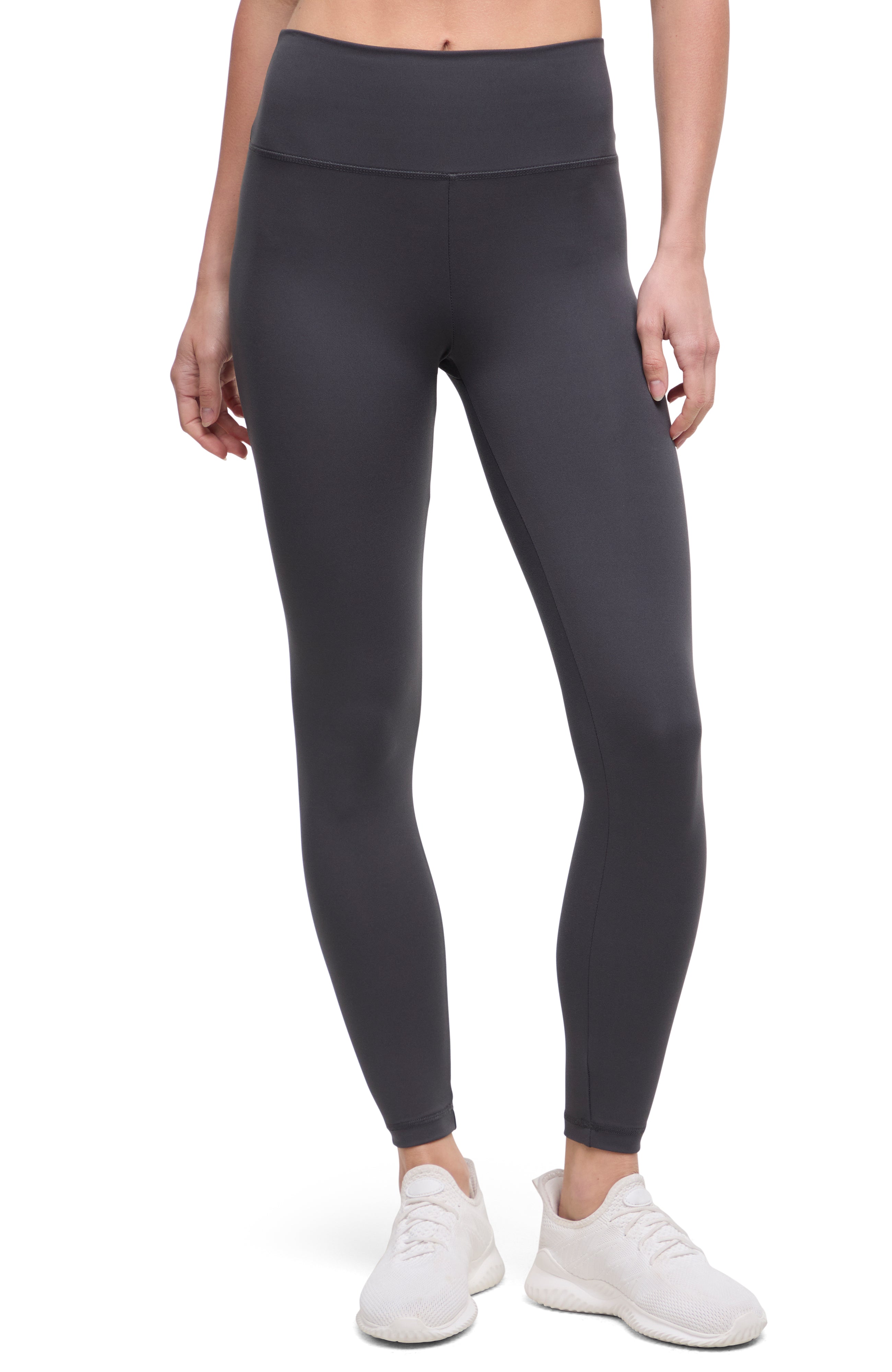 Front view of woman wearing dark gray leggings with a white background. 