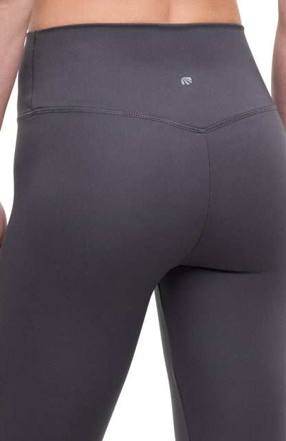 Close up back view of woman wearing dark gray leggings with a white background. 