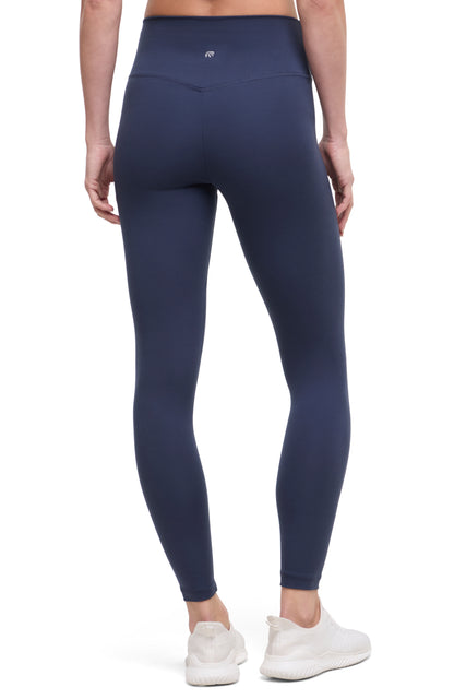 Back view of woman wearing navy leggings with a white background. 