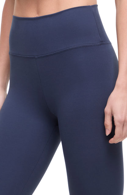 Close up front view of woman wearing navy leggings with a white background. 