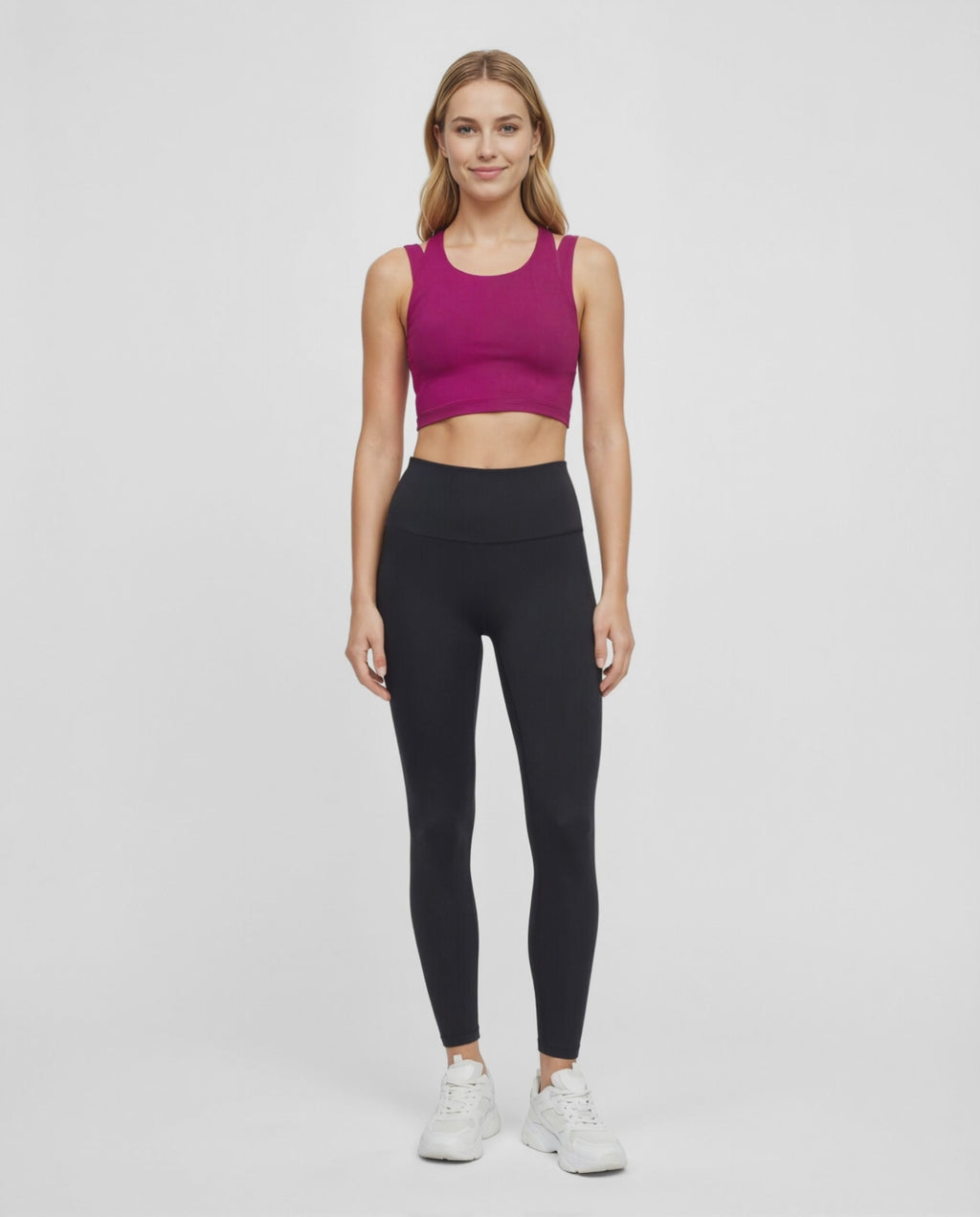 Video view of woman wearing a bright burgundy sports bra and black leggings on a white background. #color_magenta-purple