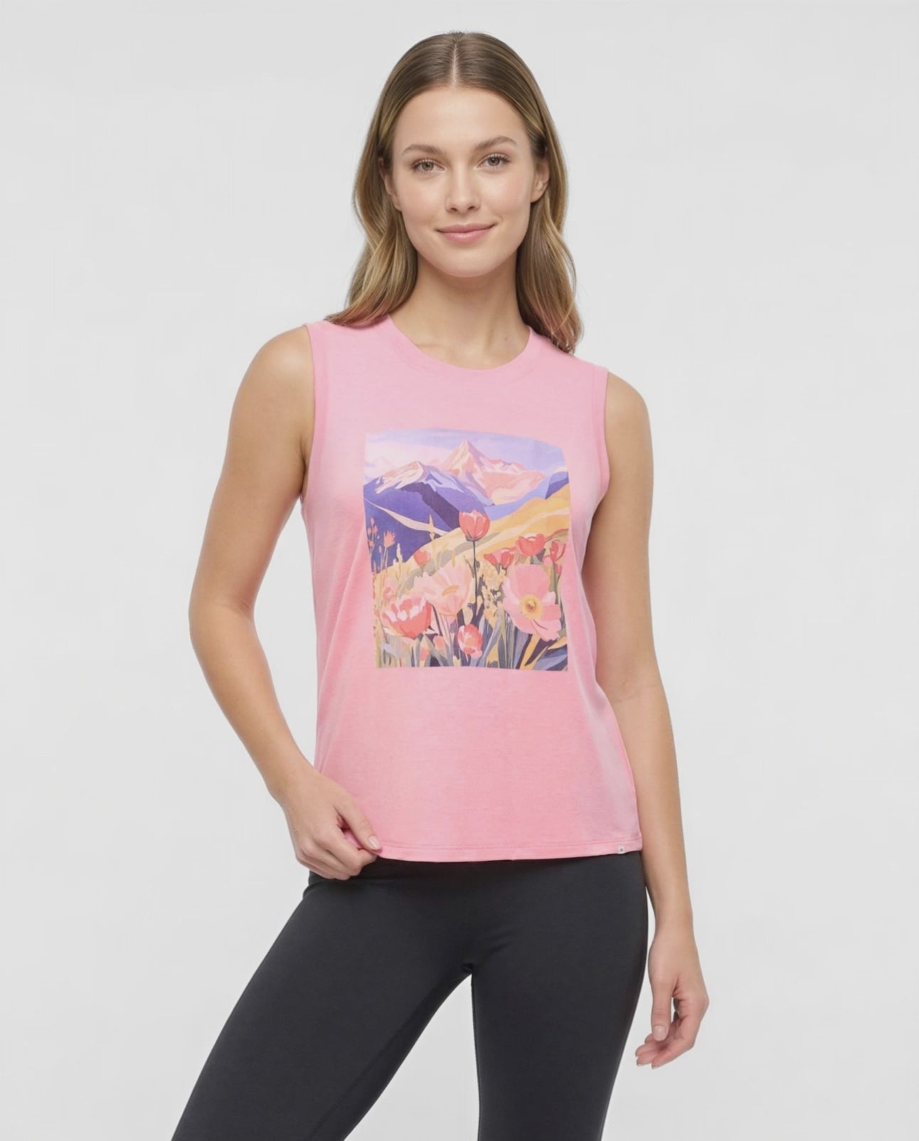 Video view of woman wearing a pink sleeveless top with a colorful floral and mountain design on a white background. 