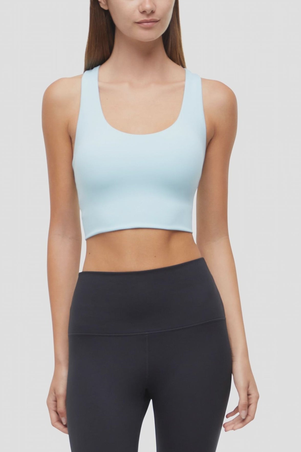 Video view of woman wearing a light blue sports bra and black leggings on a white background. #color_ocean-current