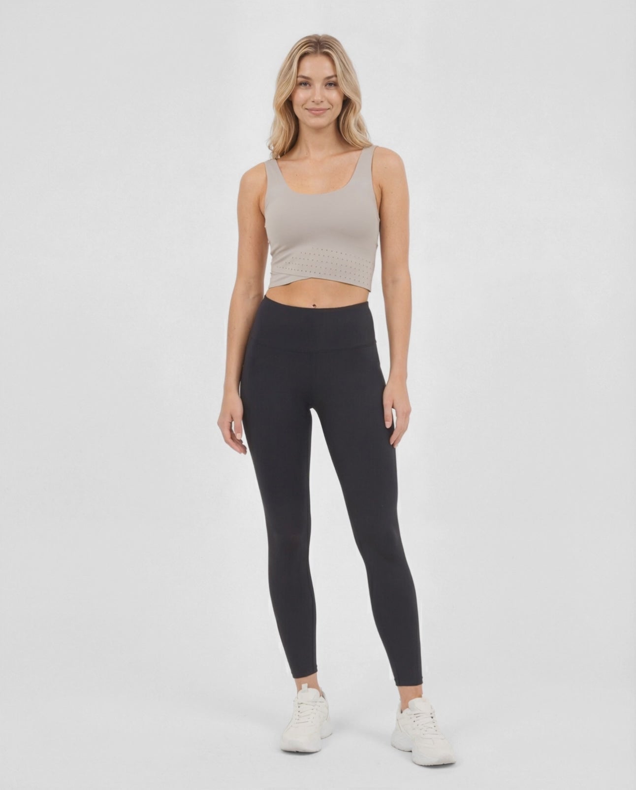 Video view of woman wearing a beige sports bra and black leggings on a white background. #color_atmosphere