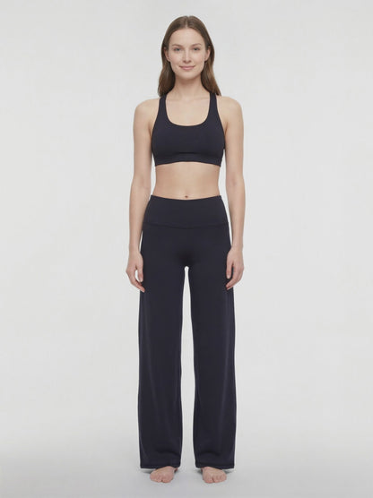 Video view of woman wearing black yoga pants on a white background. 