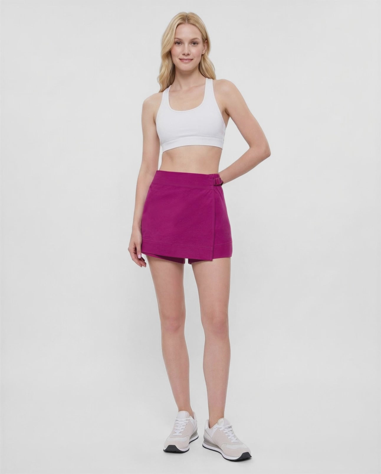 Video of woman wearing a magenta purple skort with waist clasp and white sneakers on a white background. #color_magenta-purple