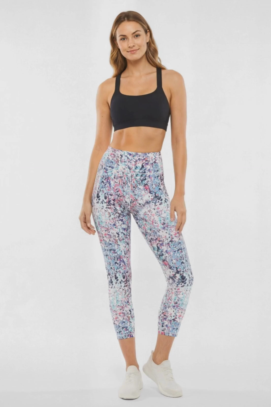 Video view of woman wearing colorful floral leggings on a white background. 