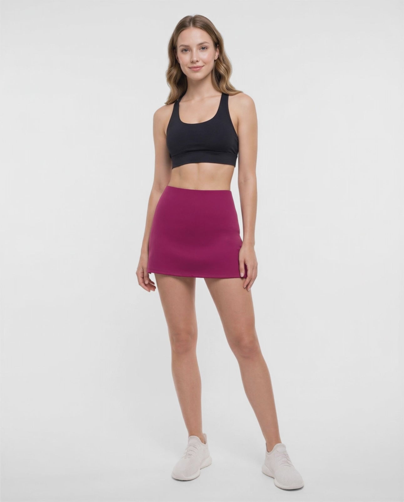 Video view of woman wearing a magenta skort and black sport bra on a white background. #color_magenta-purple