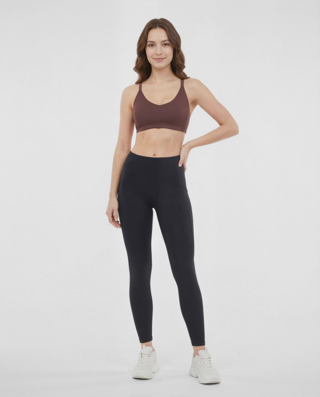Video view of woman wearing a brown sports bra and black leggings on a white background. #color_french-roast
