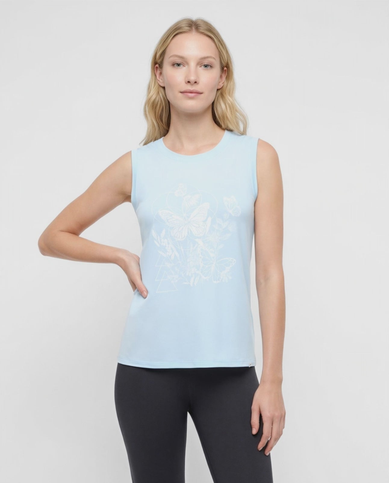 Video view of woman wearing a light blue sleeveless top with white butterflies design on a plain background. #color_heather-ocean-current-butterfly-bunch